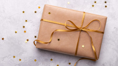 gift wrapped in gold paper with gold ribbon and gold confetti stars scattered
