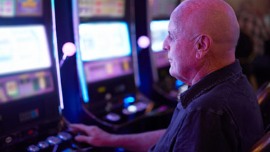 older man playing at a slot machine